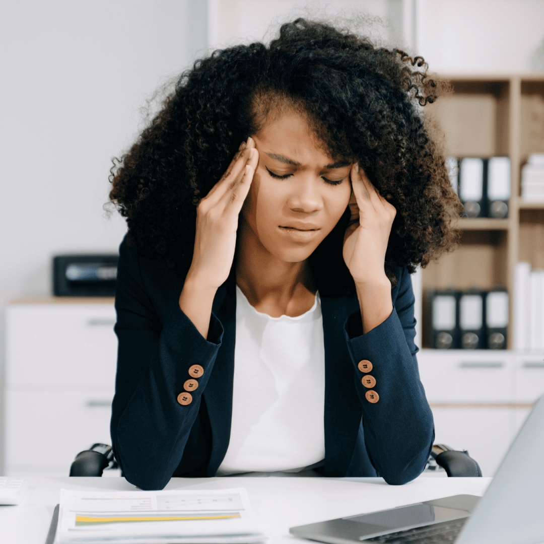Frustrated woman with head in hands at desk during tech issues.